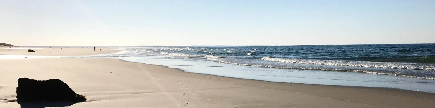 A quiet stretch of Mayflower Beach in Dennis, Massachusetts, with low waves rolling onto the sand